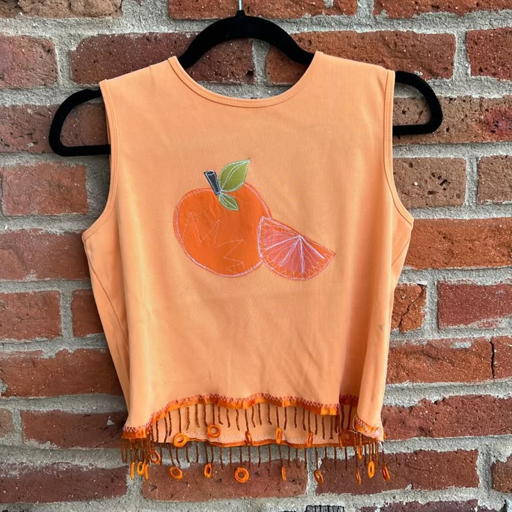 an orange crop top hanging on a brick wall