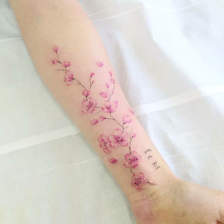 a woman's foot with pink flowers on the left side of her arm and writing in cursive font