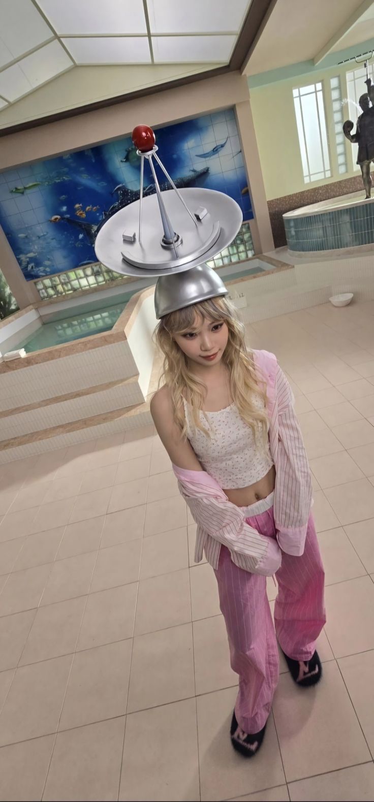 a girl in pink pants and a white top with a silver object on her head