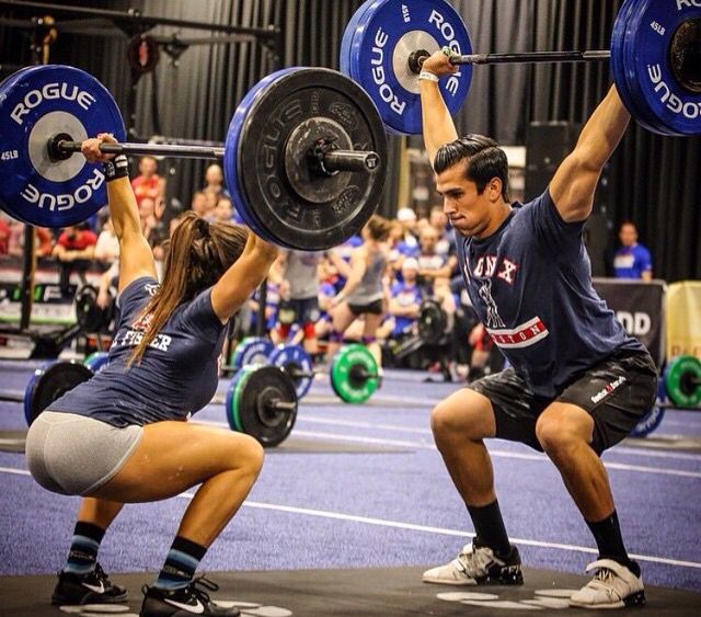 two people doing squat exercises with barbells in a gym