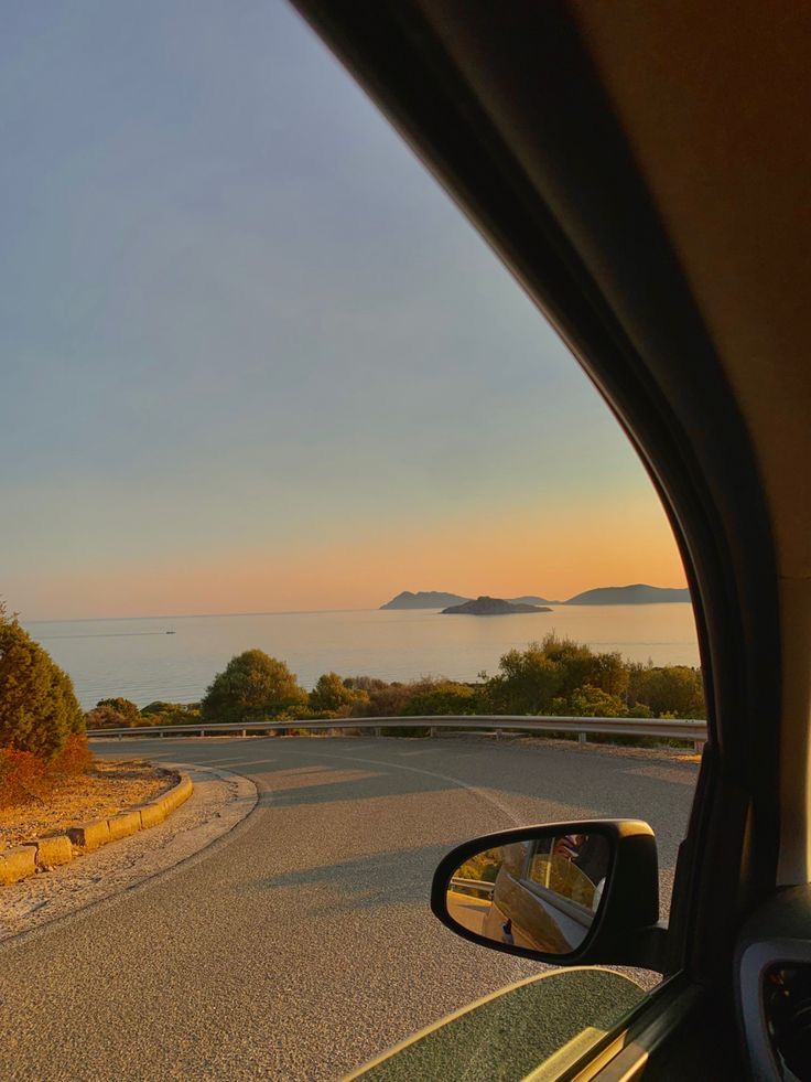 the view from inside a car looking out at an island in the ocean and mountains