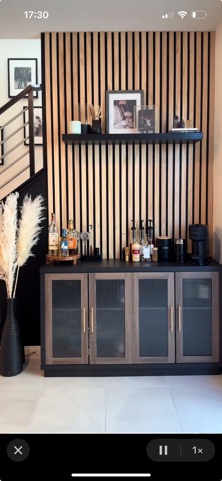 a black and white striped wall next to a wooden shelf with liquor bottles on it