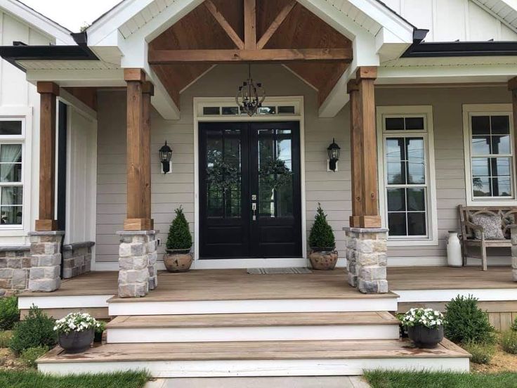 front porch with steps leading up to the entry door and two planters on either side