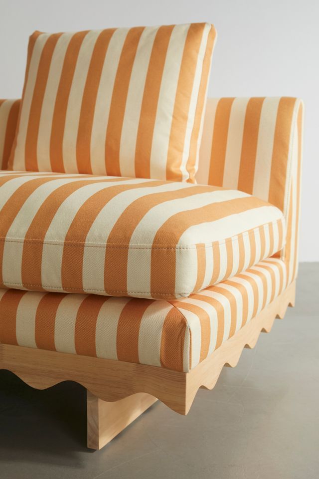 an orange and white striped couch sitting on top of a table