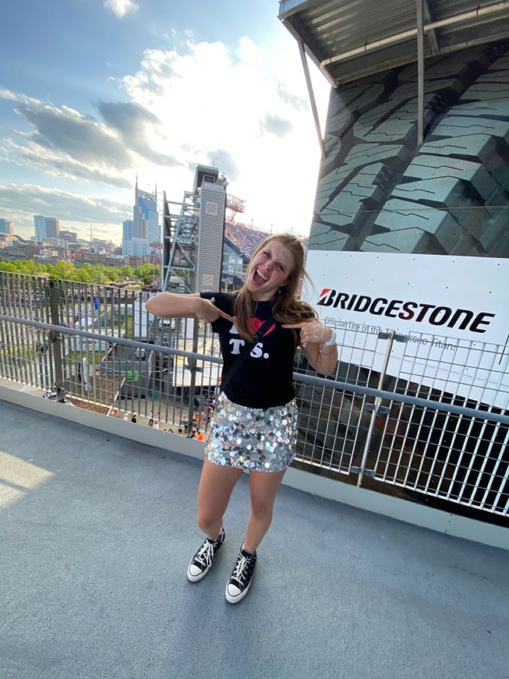 a girl is standing on the edge of a building with her arms out and smiling