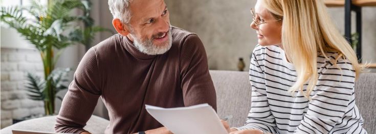 an older man and young woman sitting on a couch looking at something in front of them