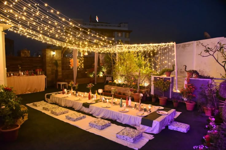 an outdoor dining area is lit up with fairy lights