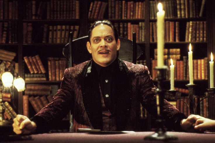 a man sitting in a chair next to a book shelf