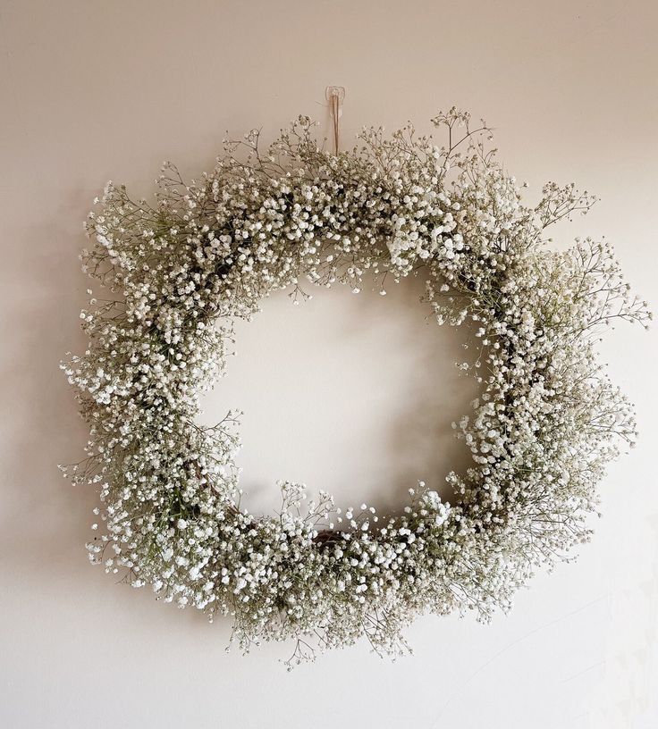 a wreath with white flowers hanging on the wall