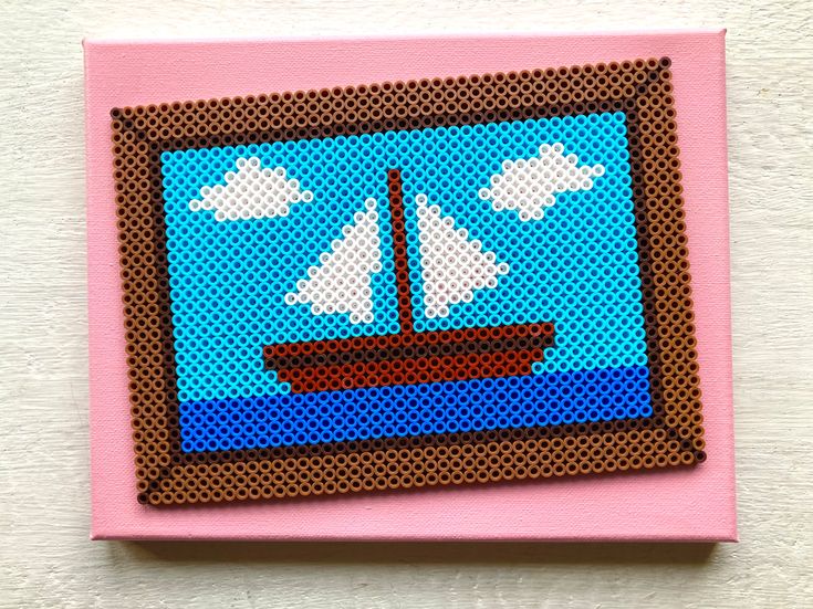 a cross stitch picture of a sailboat on the water with clouds in the sky