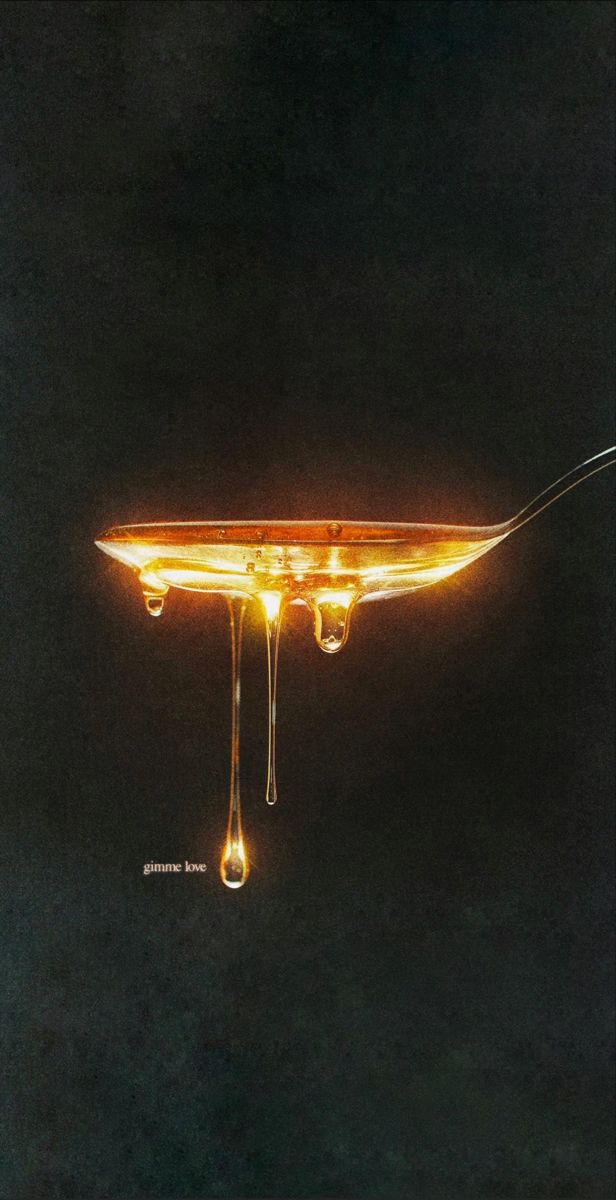 a spoon with liquid dripping from it on a black background and an image of a light bulb in the middle