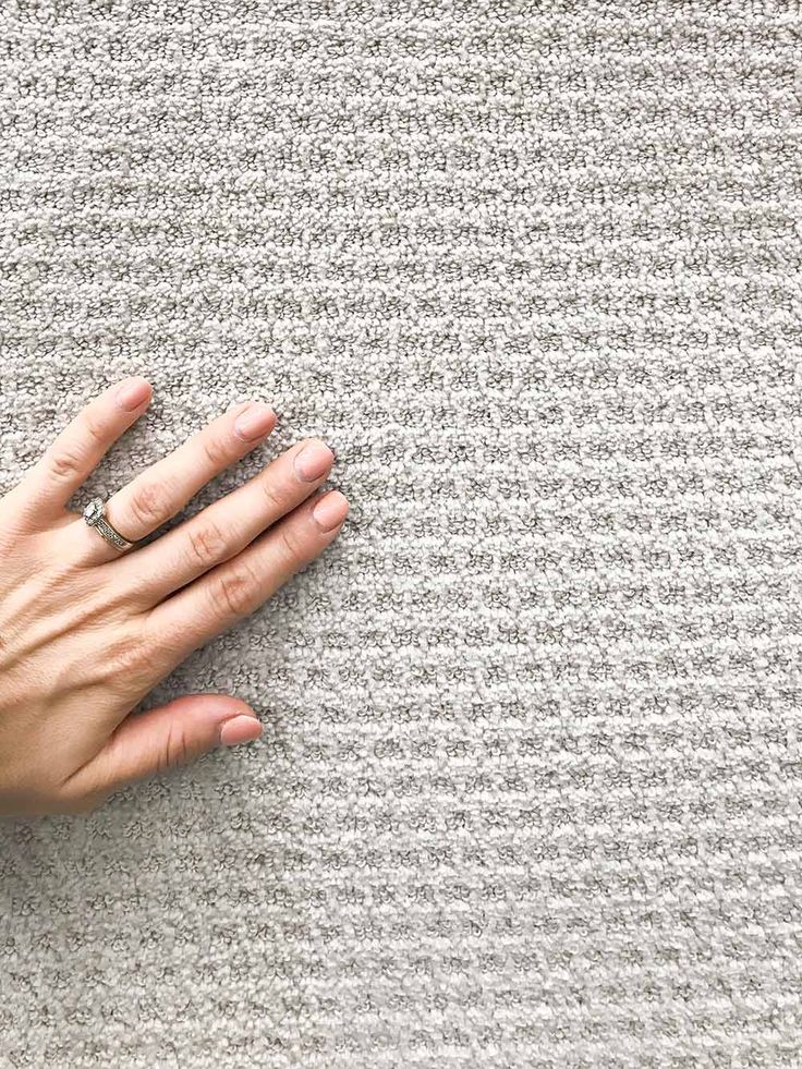 a woman's hand on top of a rug with her ring resting on it