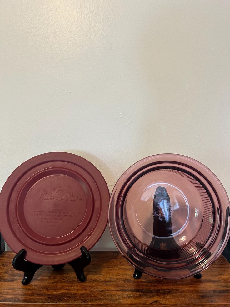 two pink plates sitting on top of a wooden table next to each other with black legs