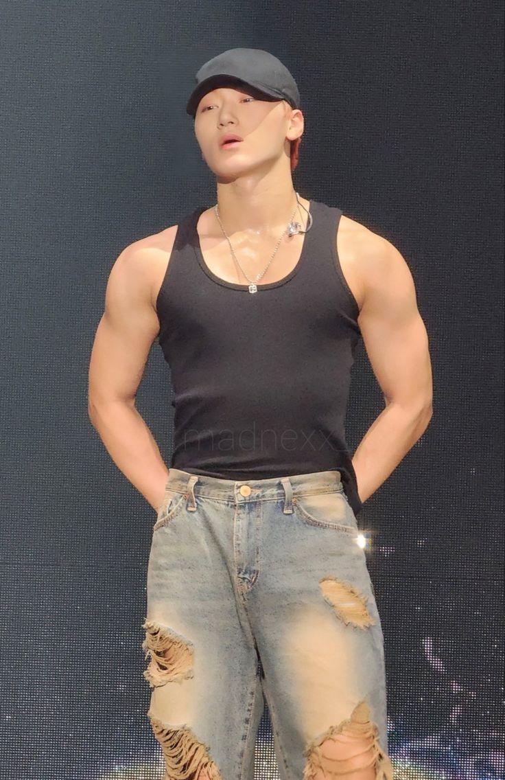 a male in a black shirt and ripped jeans is standing with his hands on his hips