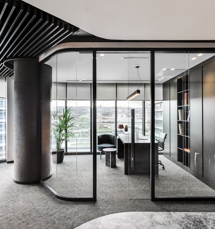 an office with glass walls and black furniture