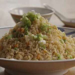 a white bowl filled with rice and vegetables on top of a table next to silverware