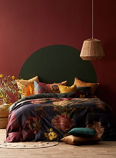 a bed in a room with red walls and wooden flooring, along with colorful pillows