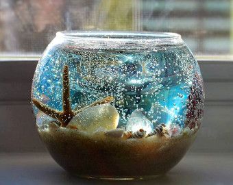 a glass bowl filled with sand and sea shells