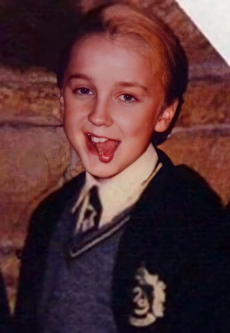 a young boy wearing a harry potter sweater and smiling at the camera with his tongue out