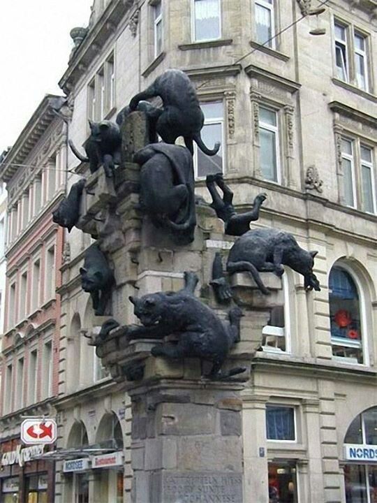 there is a statue with cats on it in front of a building