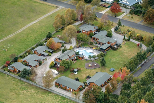 an aerial view of a home surrounded by lots of trees and houses in the background