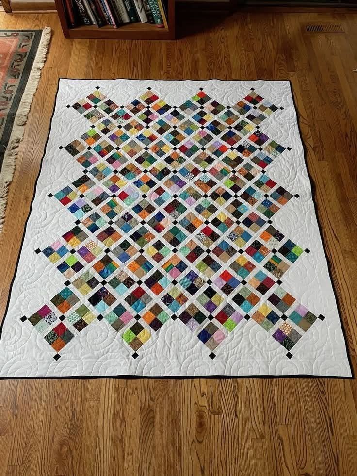 a quilt on the floor in front of a bookshelf