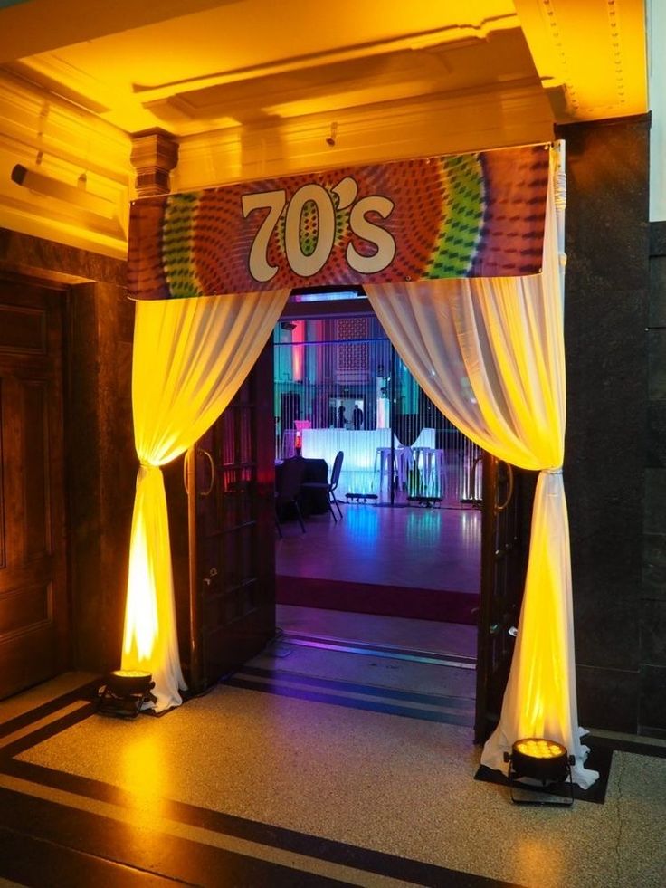 an entrance to a party with white draping and yellow lights on the floor