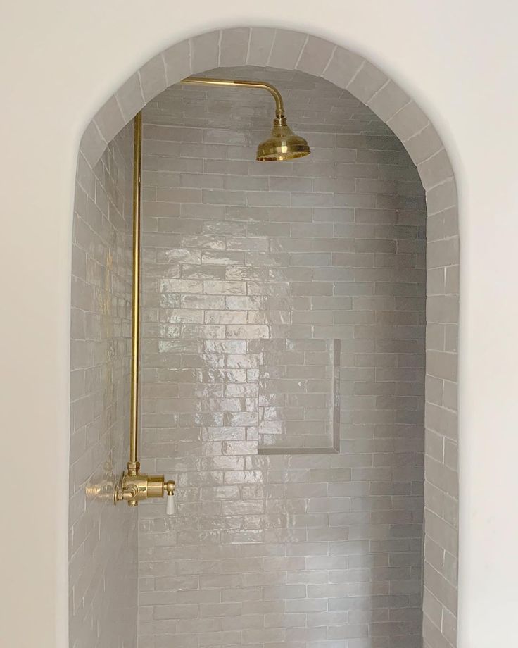 a white bathroom with gold fixtures in the shower