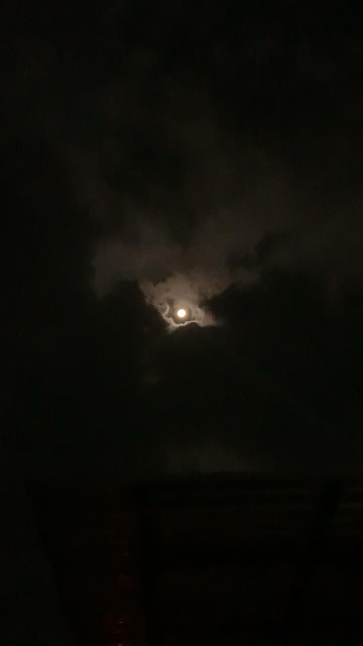 the moon is seen through some dark clouds