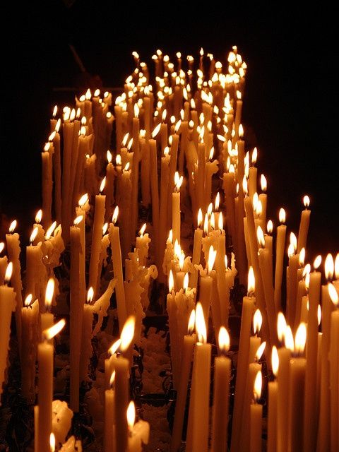 many lit candles are arranged in rows on the ground, with one candle turned upside down