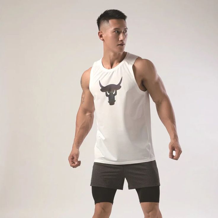 a man in shorts and a tank top is posing for the camera with his hand on his hip