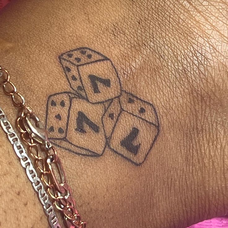 a close up of a person's wrist with dice tattoos on it and chains