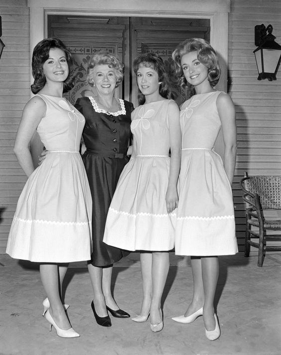 three women in dresses standing next to each other