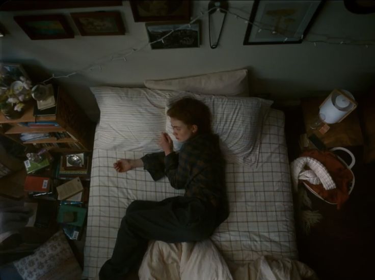 a person laying on a bed in a room with pictures and other items all around