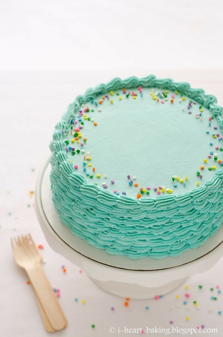 a cake with blue frosting and sprinkles on it sitting on a plate