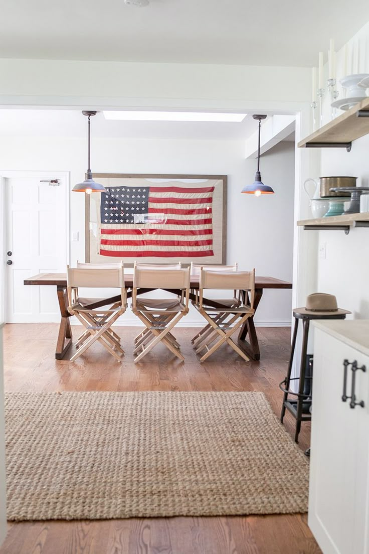 an american flag hanging over a table in a room with wood floors and white walls