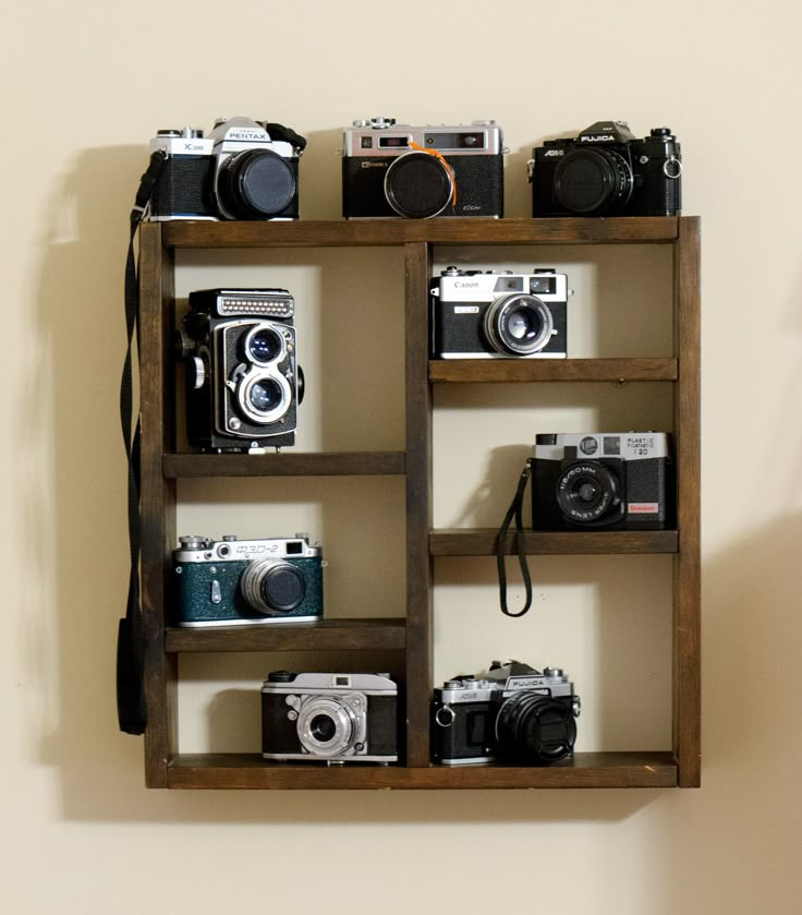 several cameras are arranged on a wooden shelf