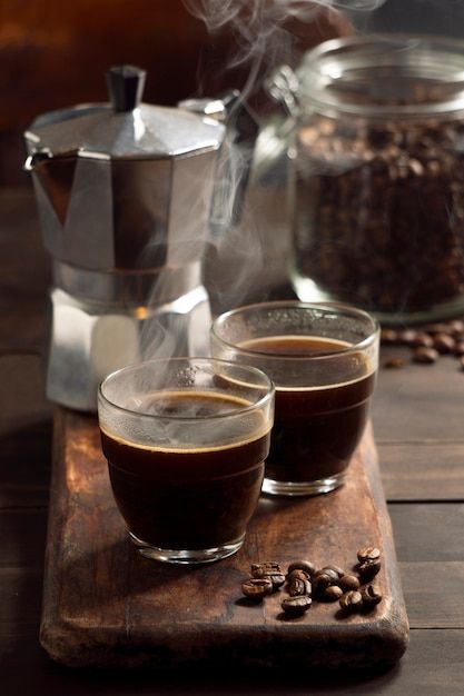 two glasses of coffee sitting on top of a wooden cutting board