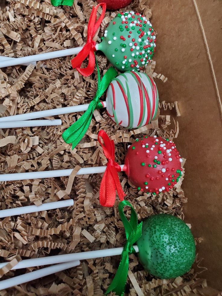 some cake pops are in a box on the ground with straw and candy canes