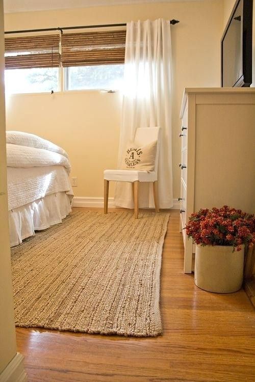 a bedroom with a bed, chair and rug on the wooden floor next to a window