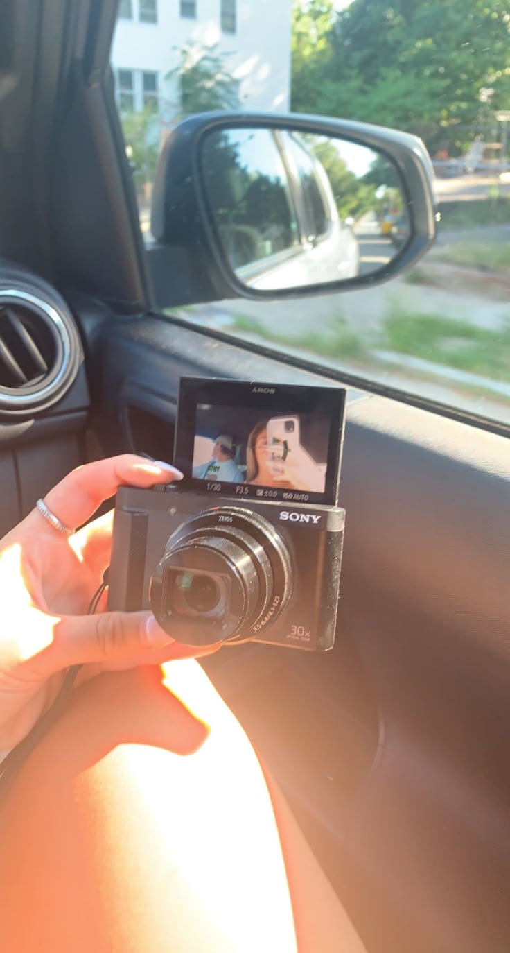 a person taking a photo in the back seat of a car with a digital camera