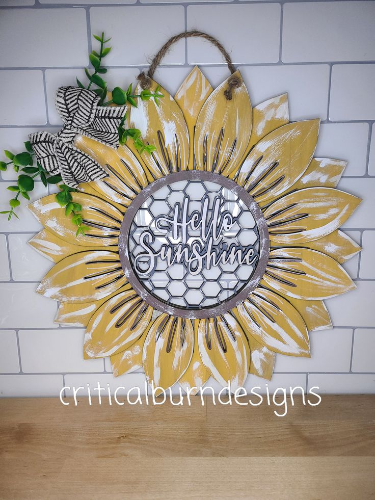 a sunflower with the words hello sunshine on it is hanging from a brick wall