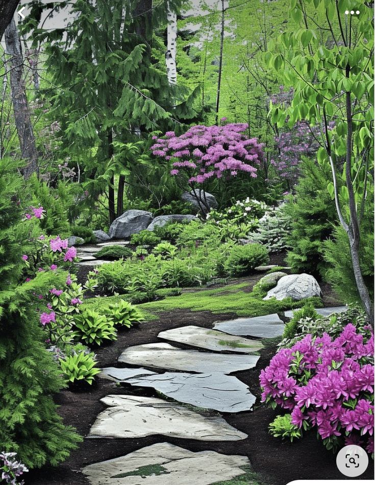 a stone path surrounded by flowers and trees