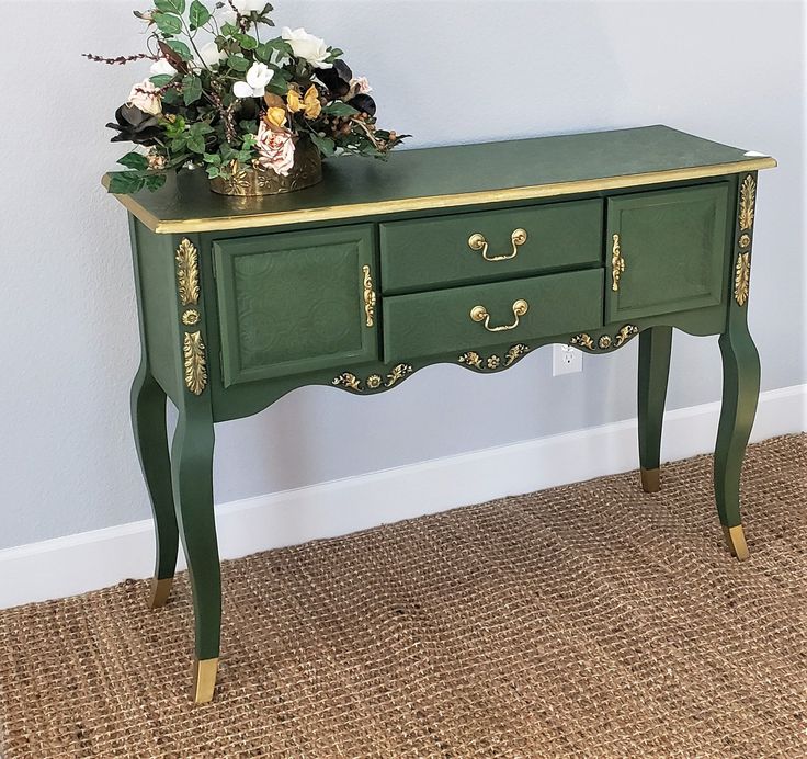 a green table with gold trim and flowers on top