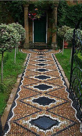 an outdoor walkway made out of cobblestones and stones with a green door in the background