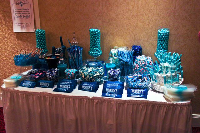 the table is covered with candy and candies for an event or celebration, including blue decorations