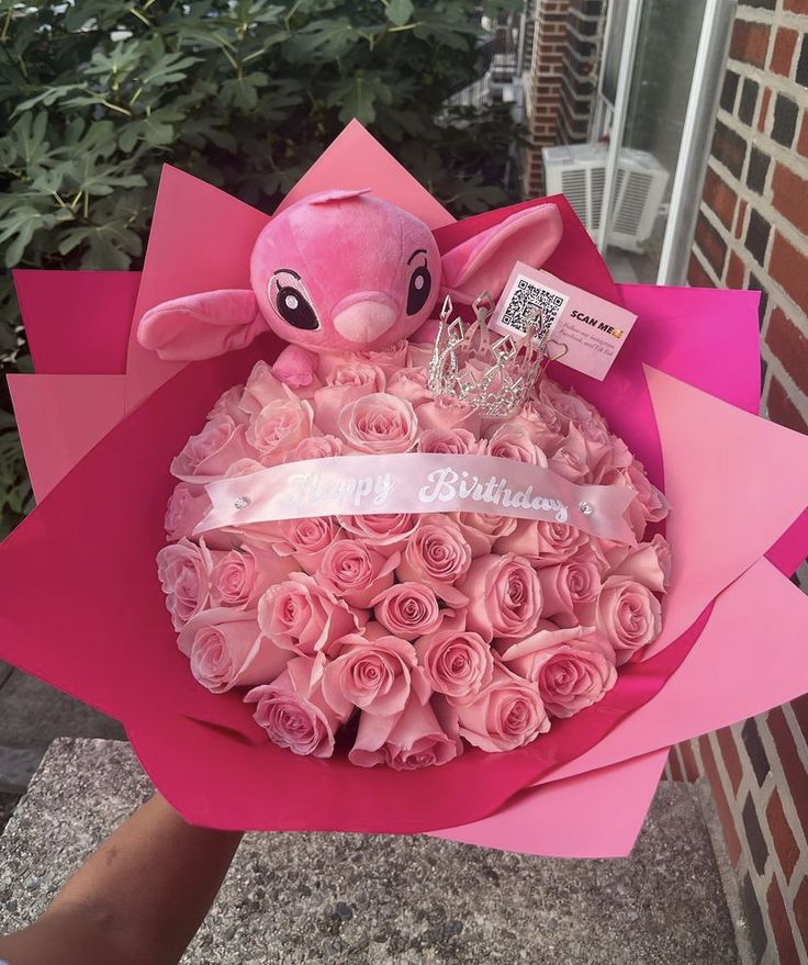 a bouquet of pink roses with a stuffed animal in the center