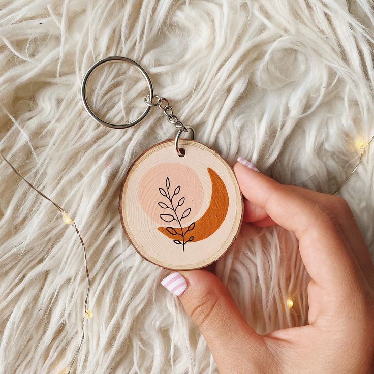 a hand holding a wooden keychain with an orange leaf on it