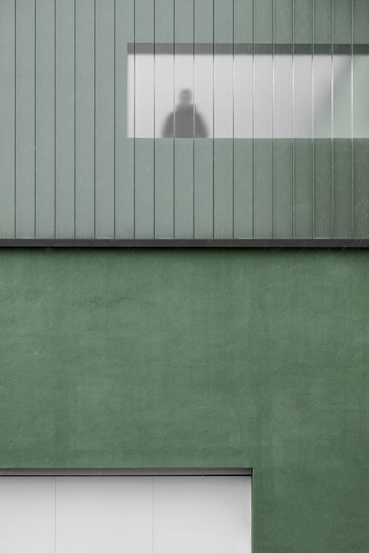 a person standing in front of a green building