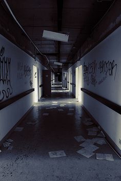 an empty hallway with graffiti on the walls